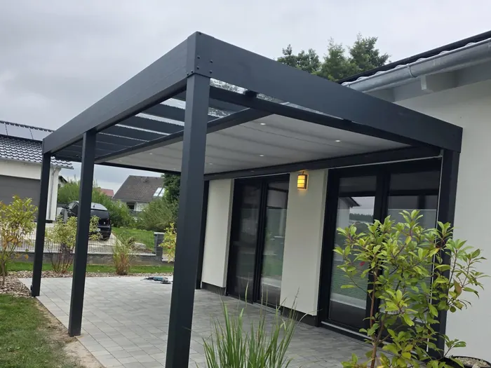 Fertiges Terrassendach aus Alu mit Glas über einer gepflasterten Terrasse