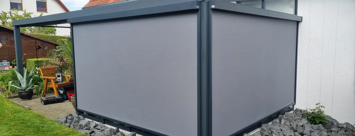 Senkrechtmarkise an der Seite eines Terrassendachs am Wohnhaus